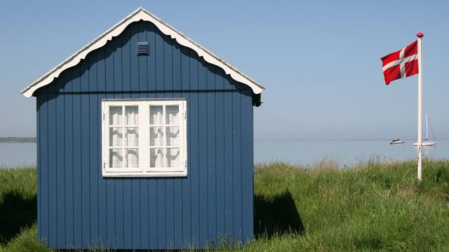 Kleines blaues Strandhaus mit weißem Fenster vor Meerblick